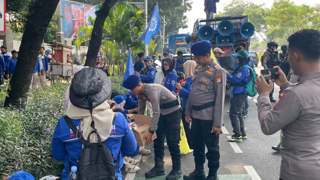 Petugas Polri membagikan air mineral kepada peserta aksi buruh di depan DPR/MPR RI